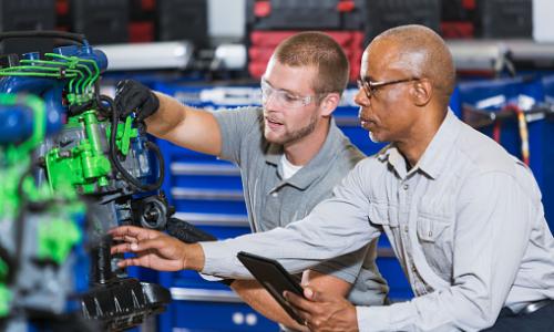 An instructor teaching a student the auto mechanic trade in a vocational class