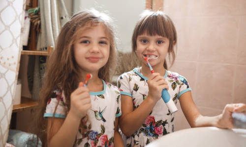 two little girls brushing their teeth in pajamas