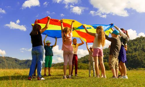 Kids playing with a rainbow parachute