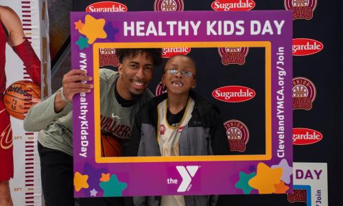Cavs player and child smile inside of a Healthy Kids Day Selfie Sign