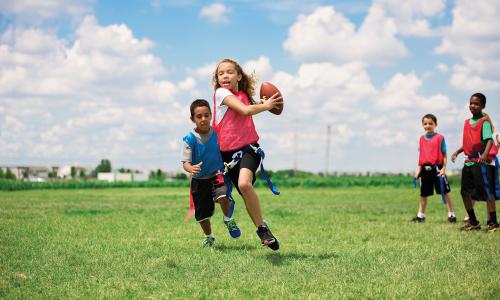 Girl playing flag football running to avoid getting tagged