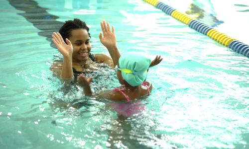 YMCA swim instructor high-fiving child after swim lesson