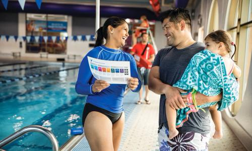 Swimming instructor talking with a father and daughter
