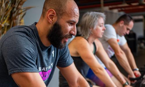 Tri at the Y contestants ride stationary bikes