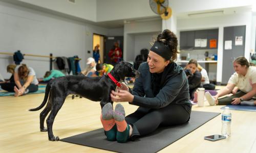 Woman pets puppy at Puppy Yoga at West Shore Family YMCA