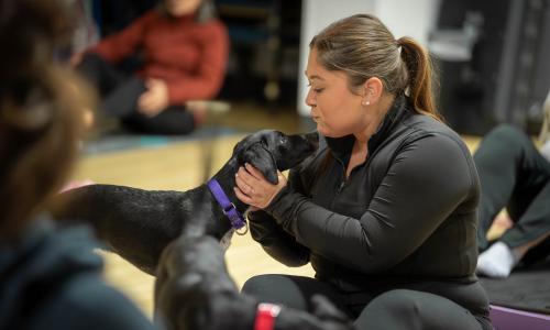 Woman pets puppy at Puppy Yoga session at West Shore Family YMCA