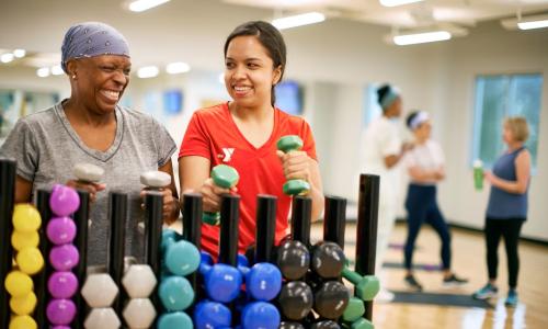 YMCA instructor helps member with weights