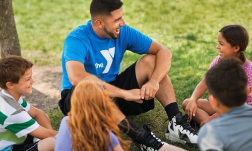 YMCA camp counselor laughs with campers