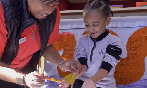 YMCA child care staff member painting a child's hand