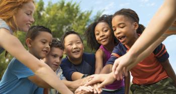 kids gathered around with hands in the middle for a team cheer