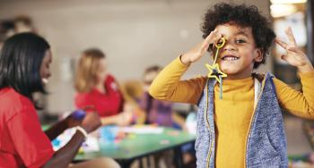 Youth Development boy in yellow  smiling at camera