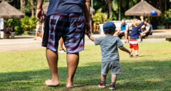 Father and son walking holding hands in the grass