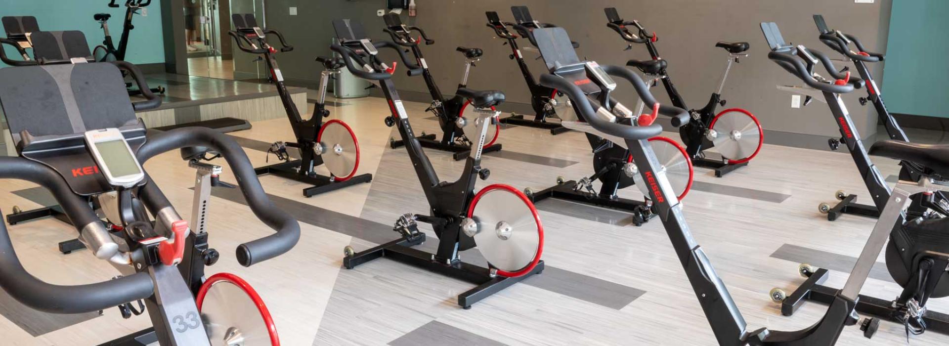 Image shows a cycle studio with many upright stationary spinning bikes.