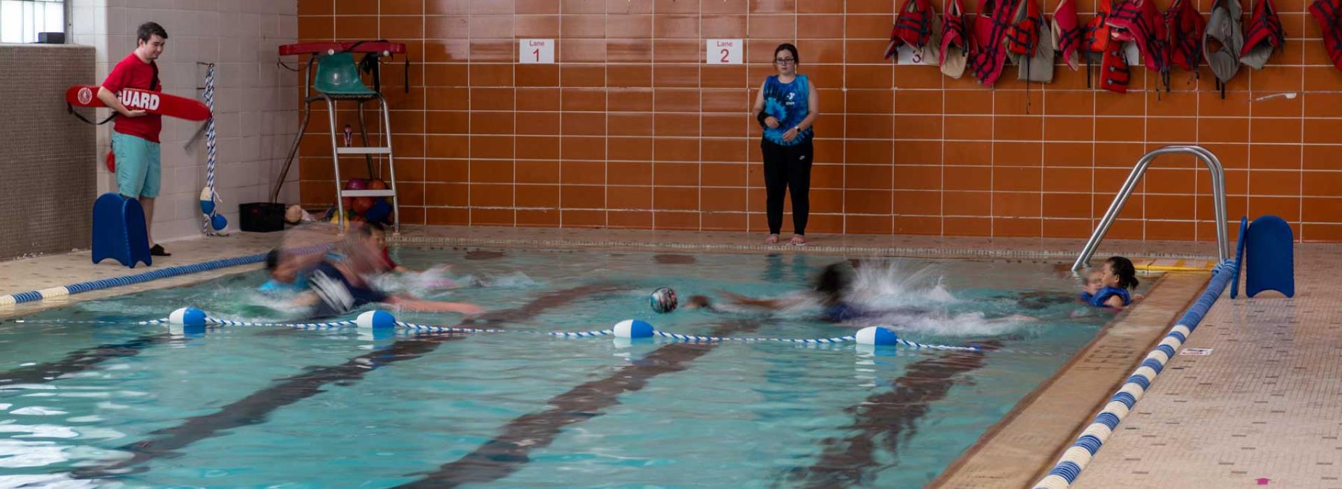 Image shows the West Park pool with 3 lanes. Shallow end is separated for members to play and swim. Image shows members splashing and swimming.